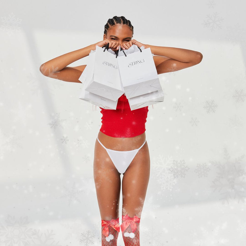 model wearing white string nix thong and holding shopping bags. Snow coming down